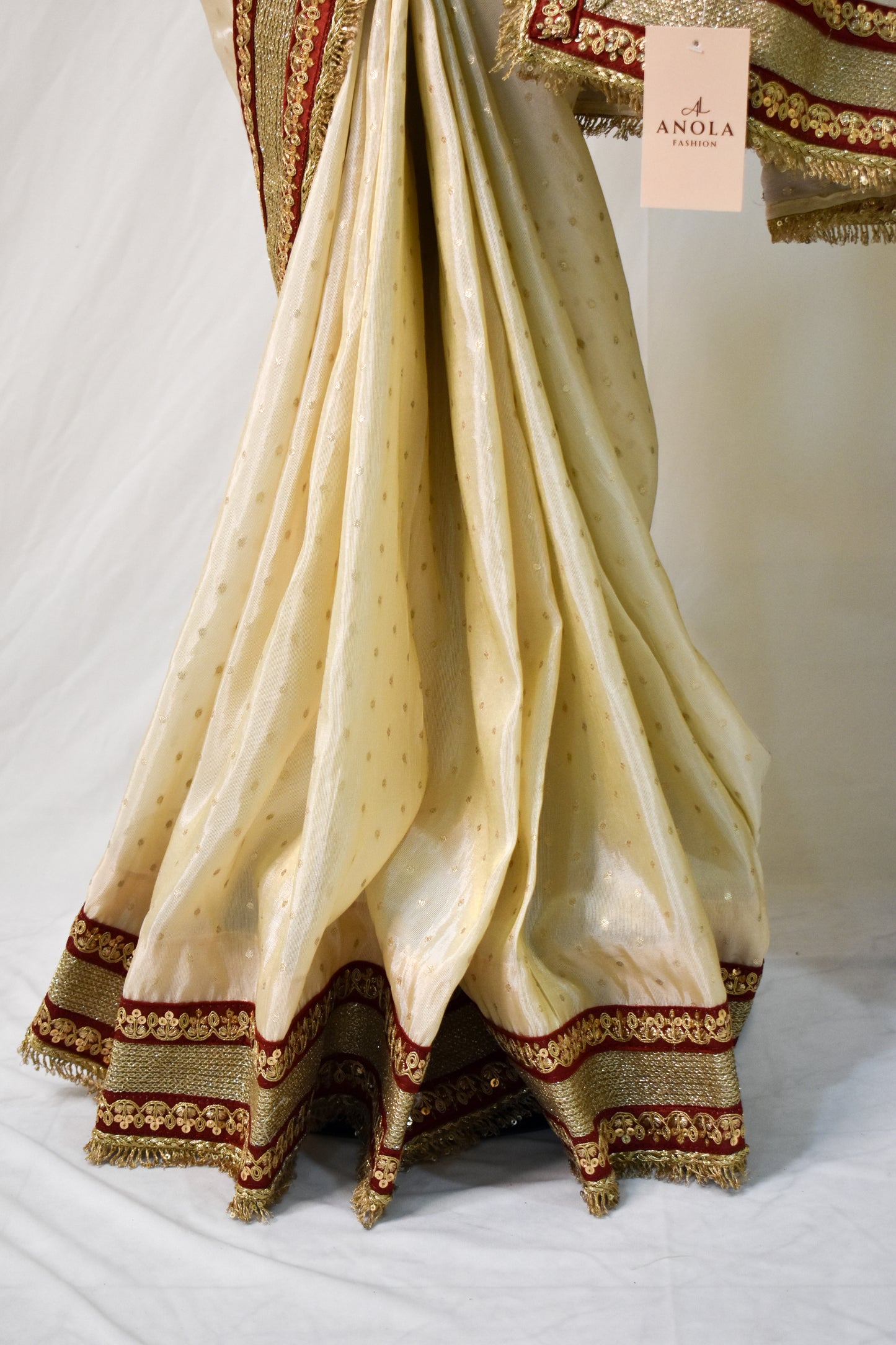 IVORY TISSUE SAREE WITH HEAVY MAROON ZARI BORDER AND FRINGE DETAILING.