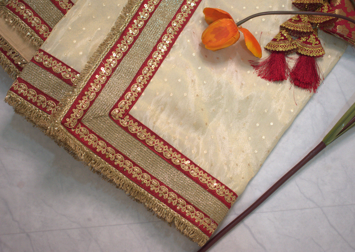 IVORY TISSUE SAREE WITH HEAVY MAROON ZARI BORDER AND FRINGE DETAILING.